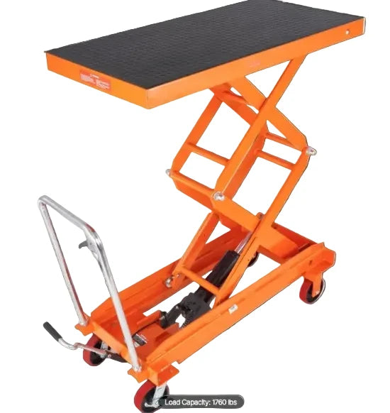 Hydraulic lift table cart transporting heavy industrial materials inside a warehouse facility.
